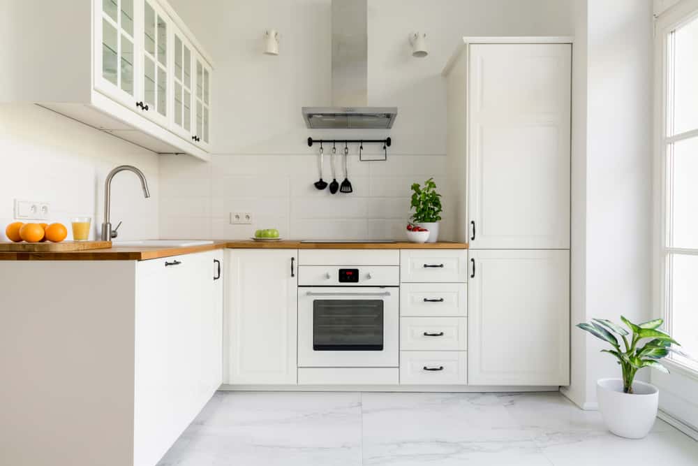 Compact white kitchen designs with wooden countertops and built in oven setup