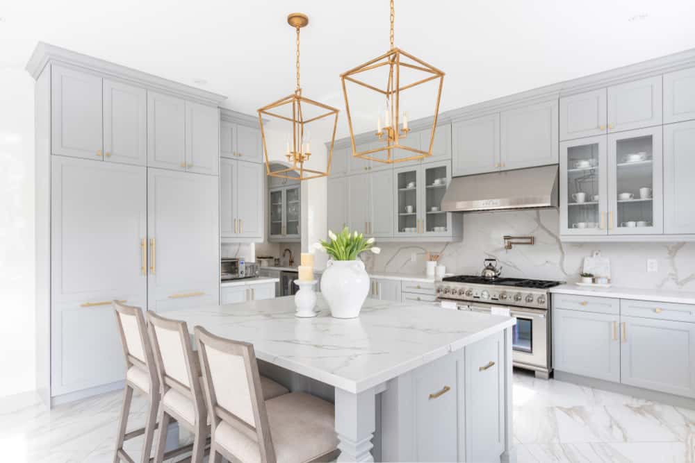 Elegant white kitchen designs with marble island and gold pendant lighting accents