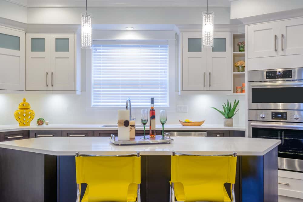 Vibrant white kitchen designs with yellow chairs and dual built in stainless steel ovens