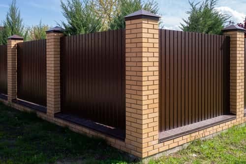 Brick boundary wall design with brown metal fencing panels