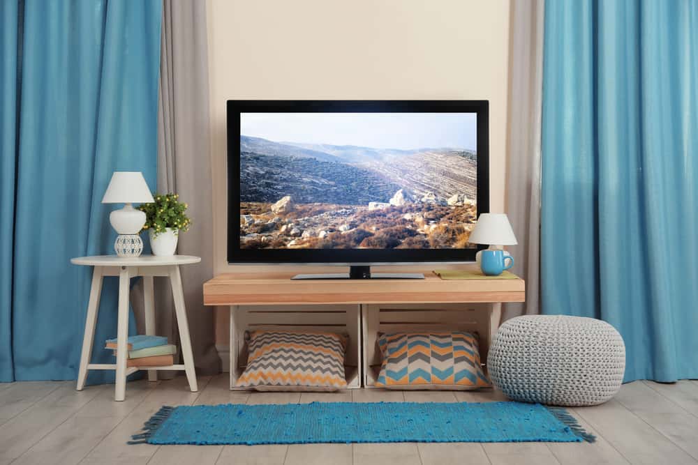 Cozy hide TV wires setup with pillows, lamps, and curtain backdrop