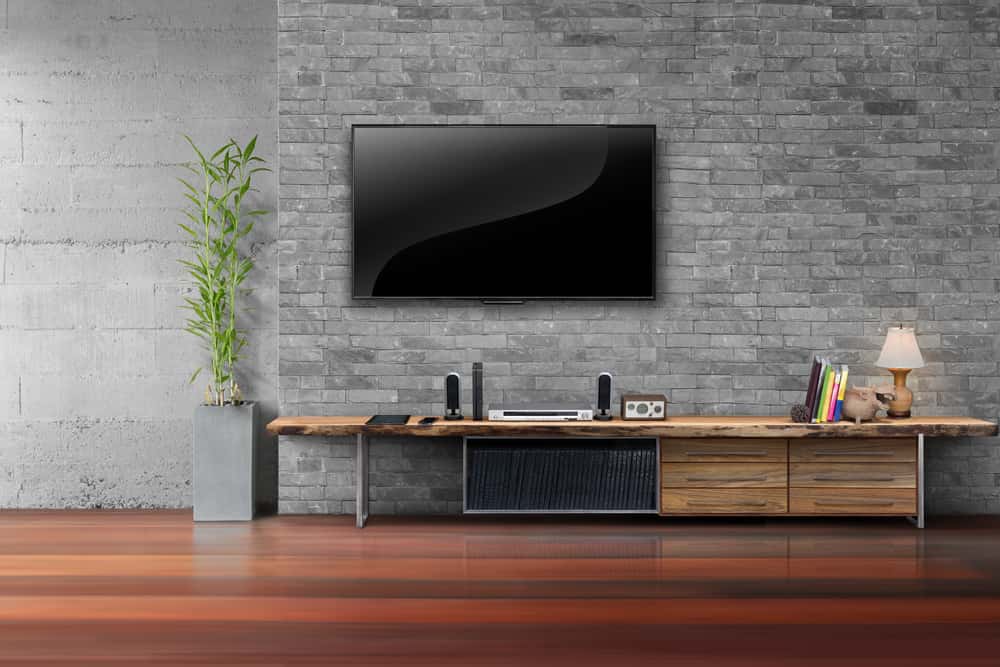 Rustic hide TV wires setup with stone wall and wooden console shelf