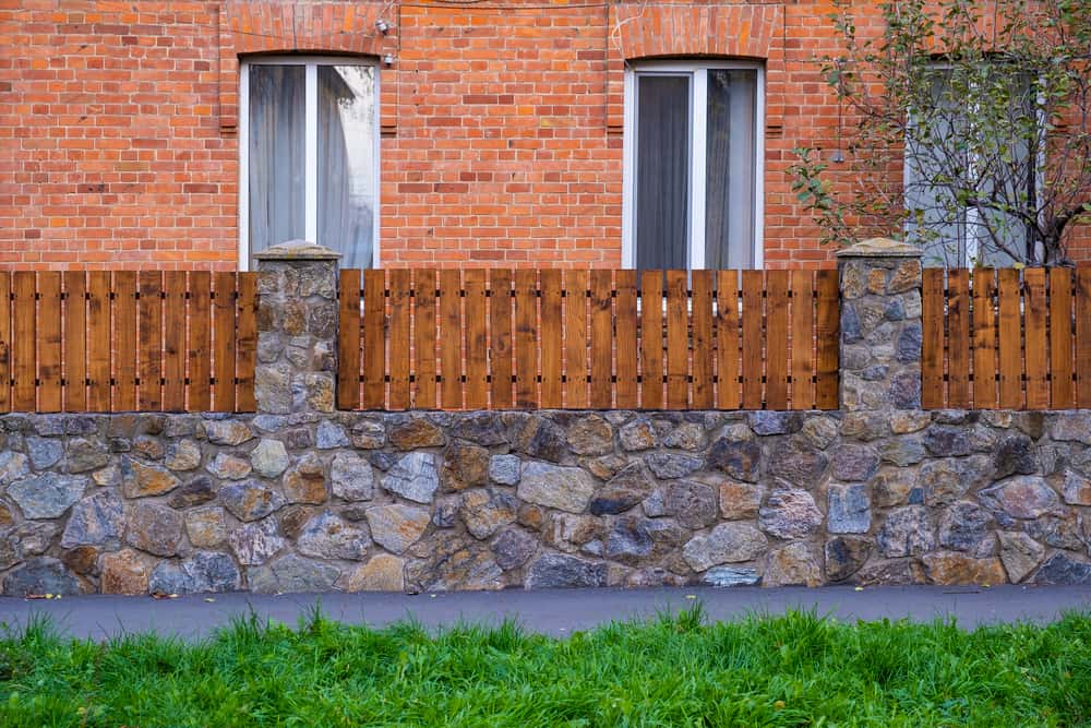 Rustic boundary wall design with stone base and wood panels