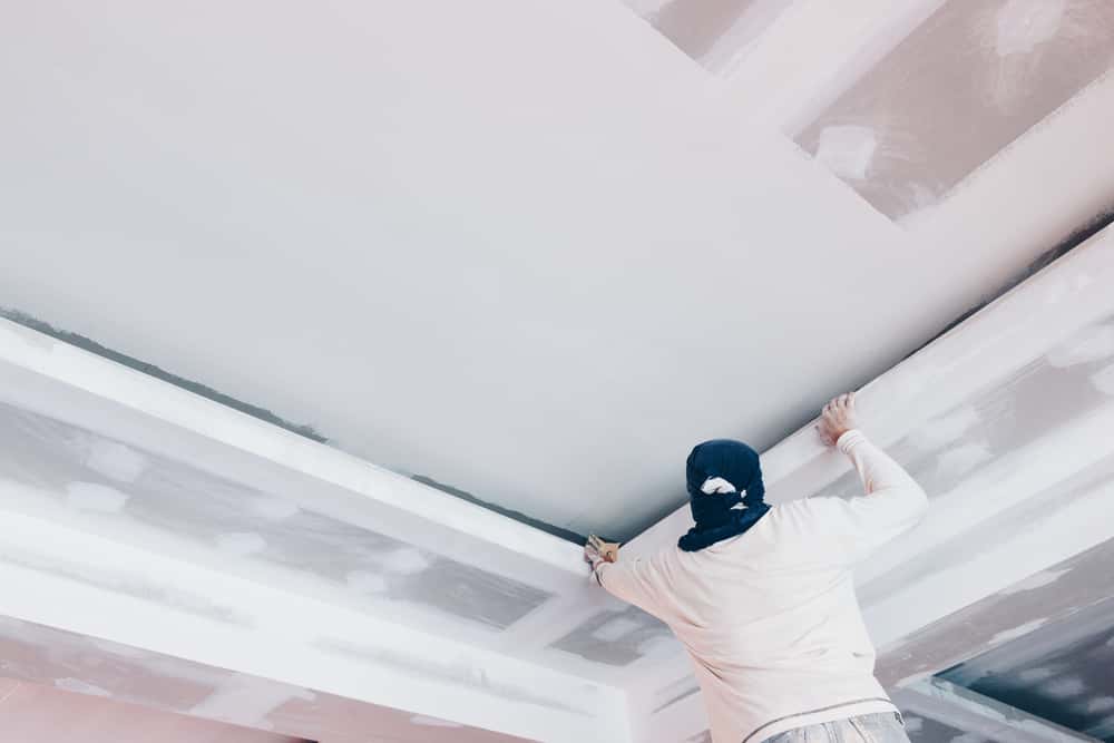 Worker installing gypsum vs pop ceiling boards for modern false ceiling design