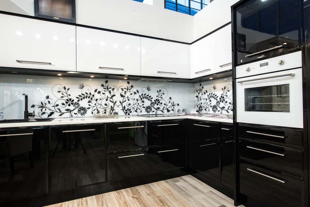 Glossy kitchen laminate designs with black and white cabinets and floral backsplash