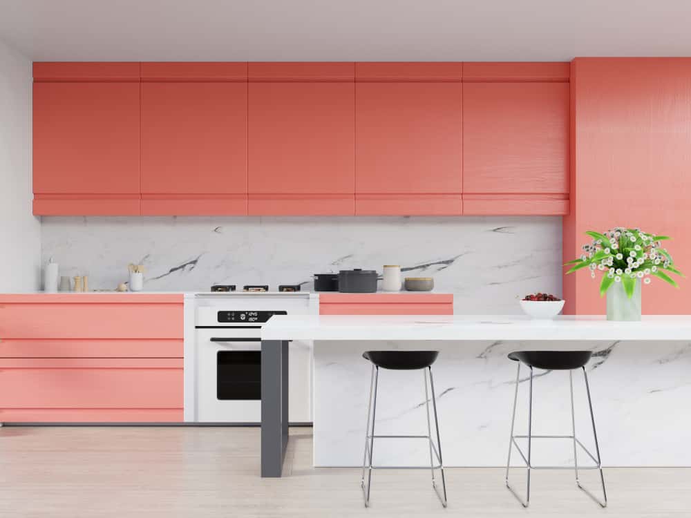 Vibrant mid century kitchen cabinets in coral with white marble backsplash