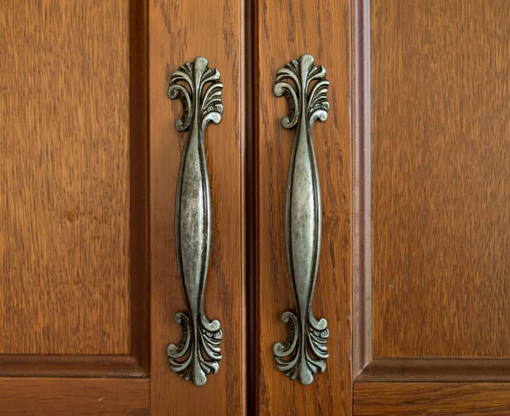 Antique wardrobe handle on wooden wardrobe with carved detailing