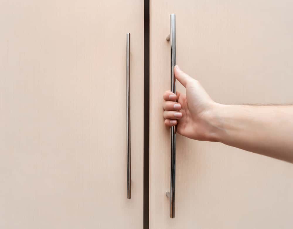 Minimal wardrobe handle design in stainless steel on wooden shutter