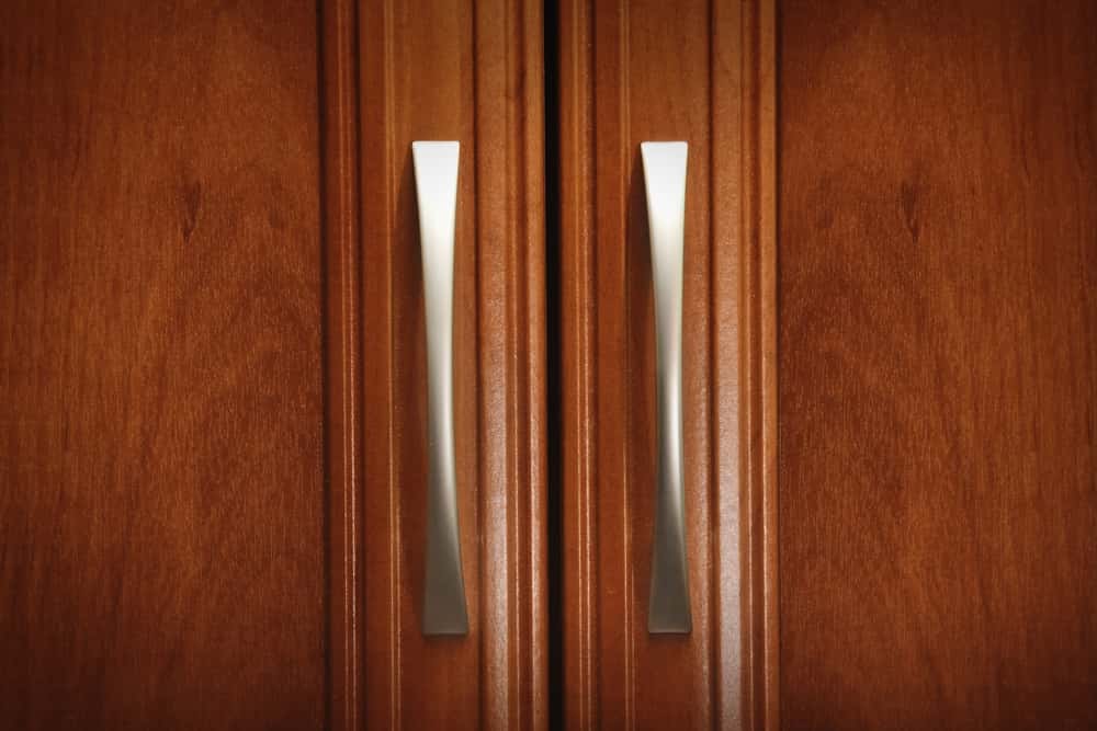 Classic wardrobe handle with metallic finish on wooden shutter