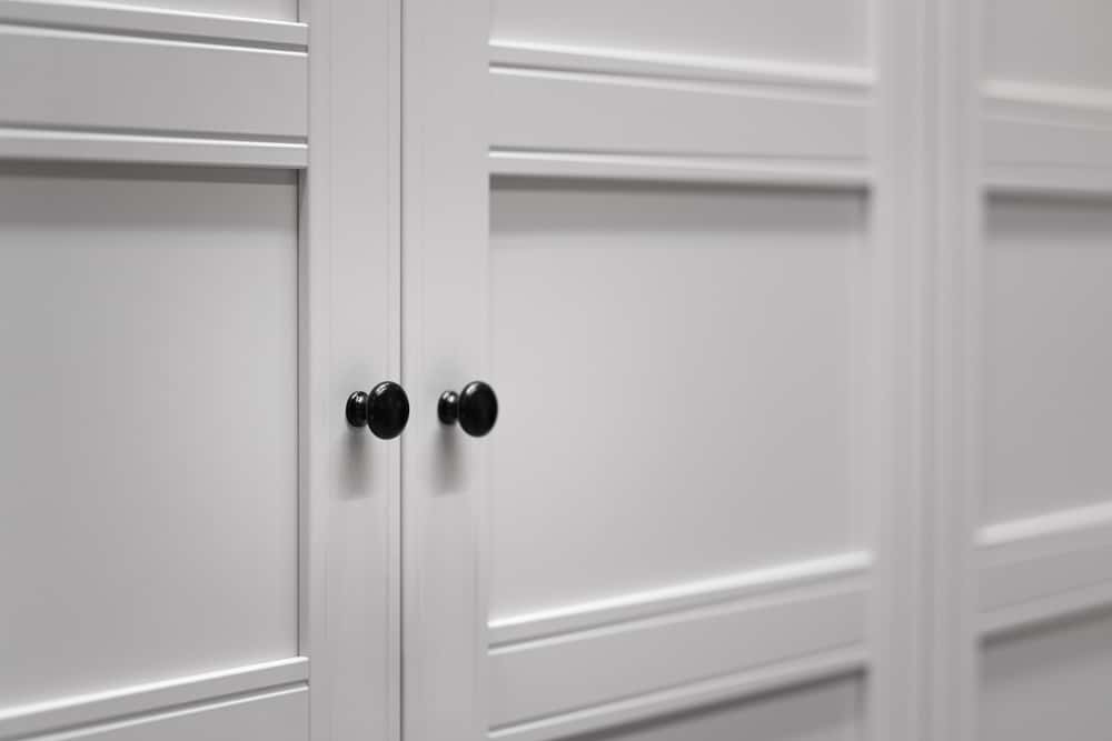 Classic wardrobe handle design with round black knobs on white panels