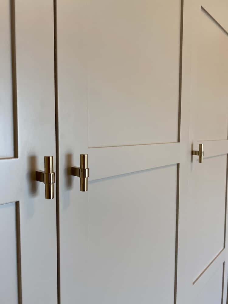 Modern wardrobe handle with sleek gold finish on paneled doors