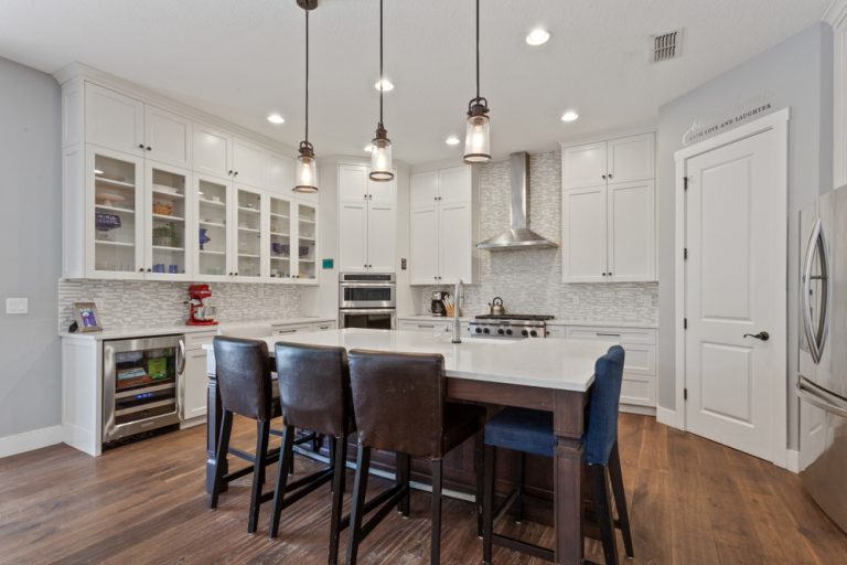 Spacious modular kitchen design with loft featuring white cabinets and large island with seating