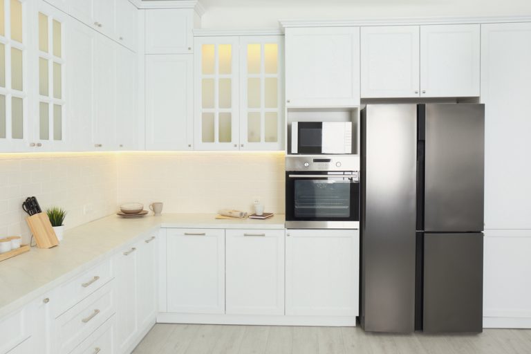 Elegant modular kitchen with loft featuring white cabinets and modern stainless steel appliances