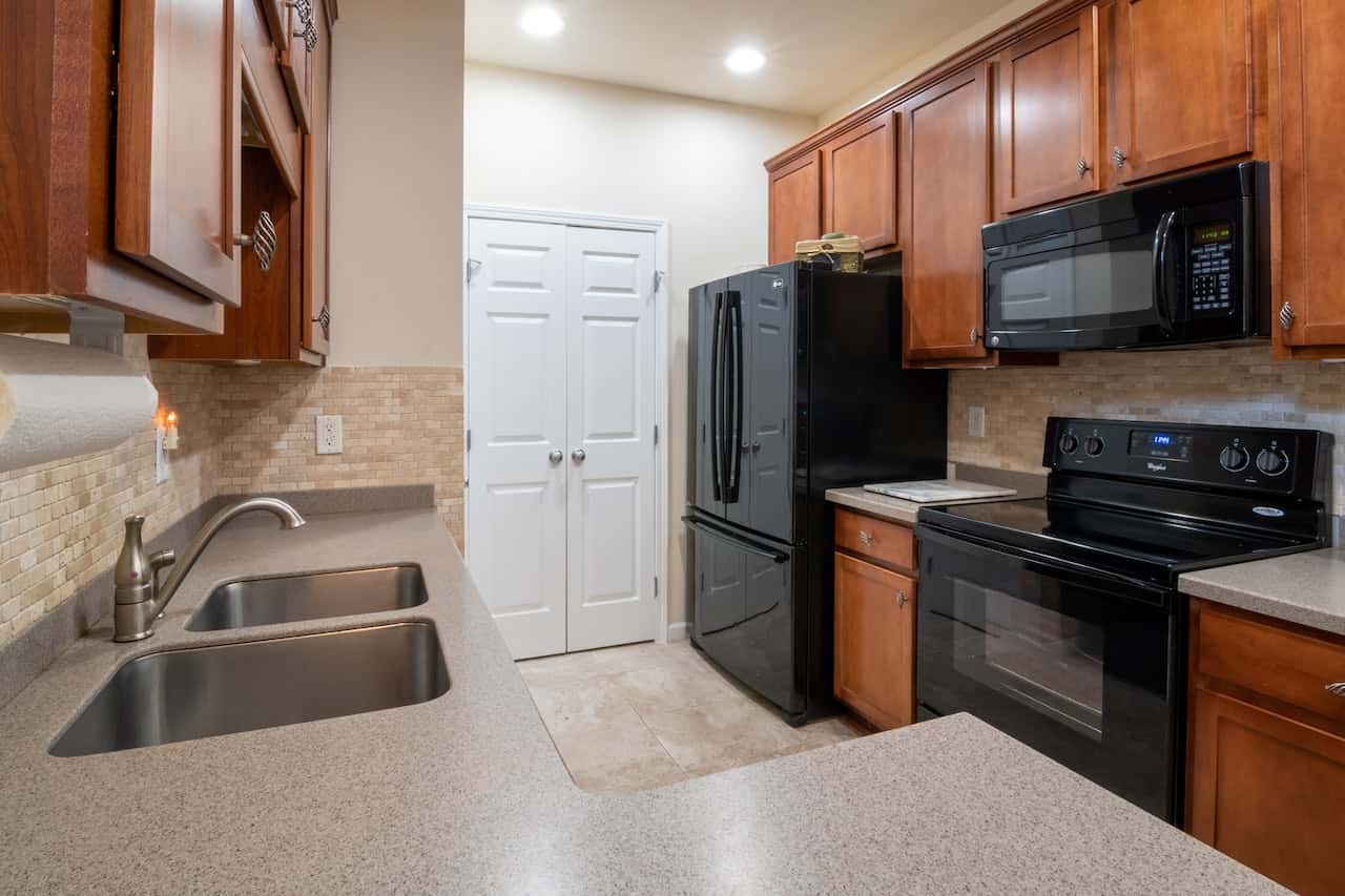 Double white kitchen door designs paired with warm wood and black appliance finishes