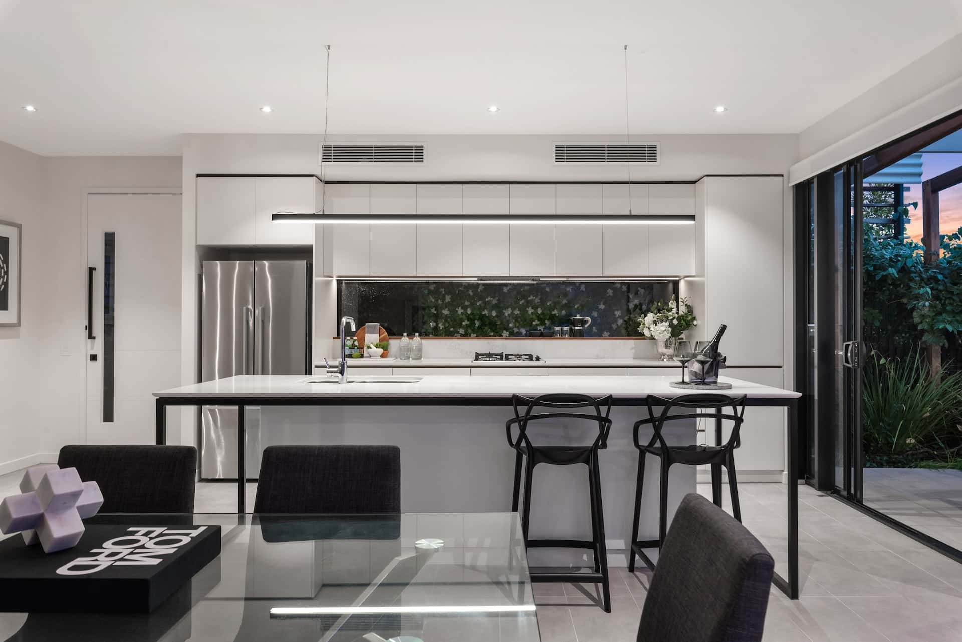 Sleek kitchen door designs complementing a modern white island and glass sliding wall