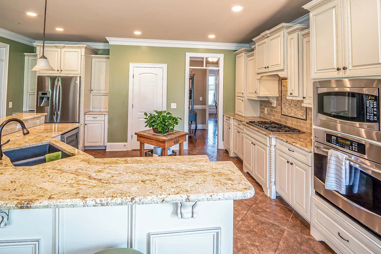 Elegant kitchen cupboard door designs with off-white cabinets and warm stone counters