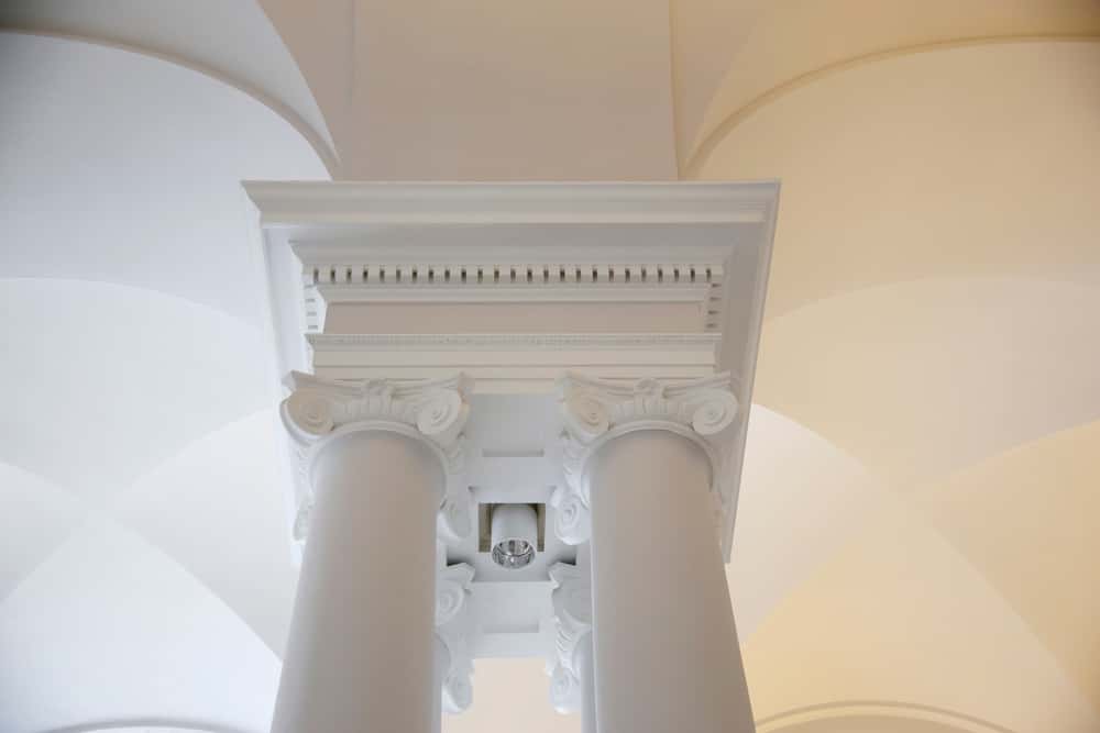 Roman-inspired cement ceiling design with detailed pillar and cornice carvings