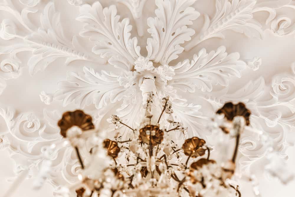 Ornamental cement ceiling design with floral medallion and vintage chandelier