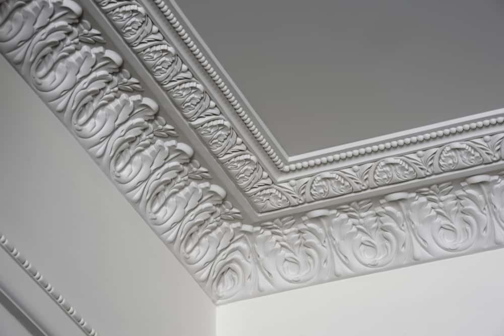 Ornate cement ceiling design with intricate corner carvings and floral border trims