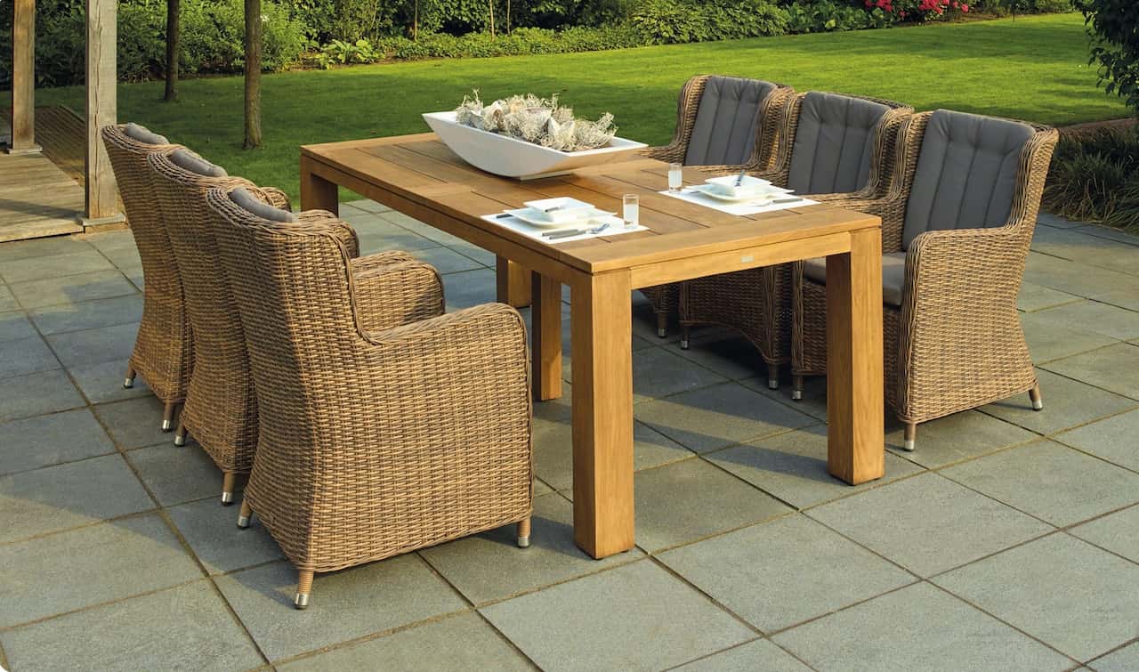 Elegant garden sitout design with wooden dining table and wicker chairs