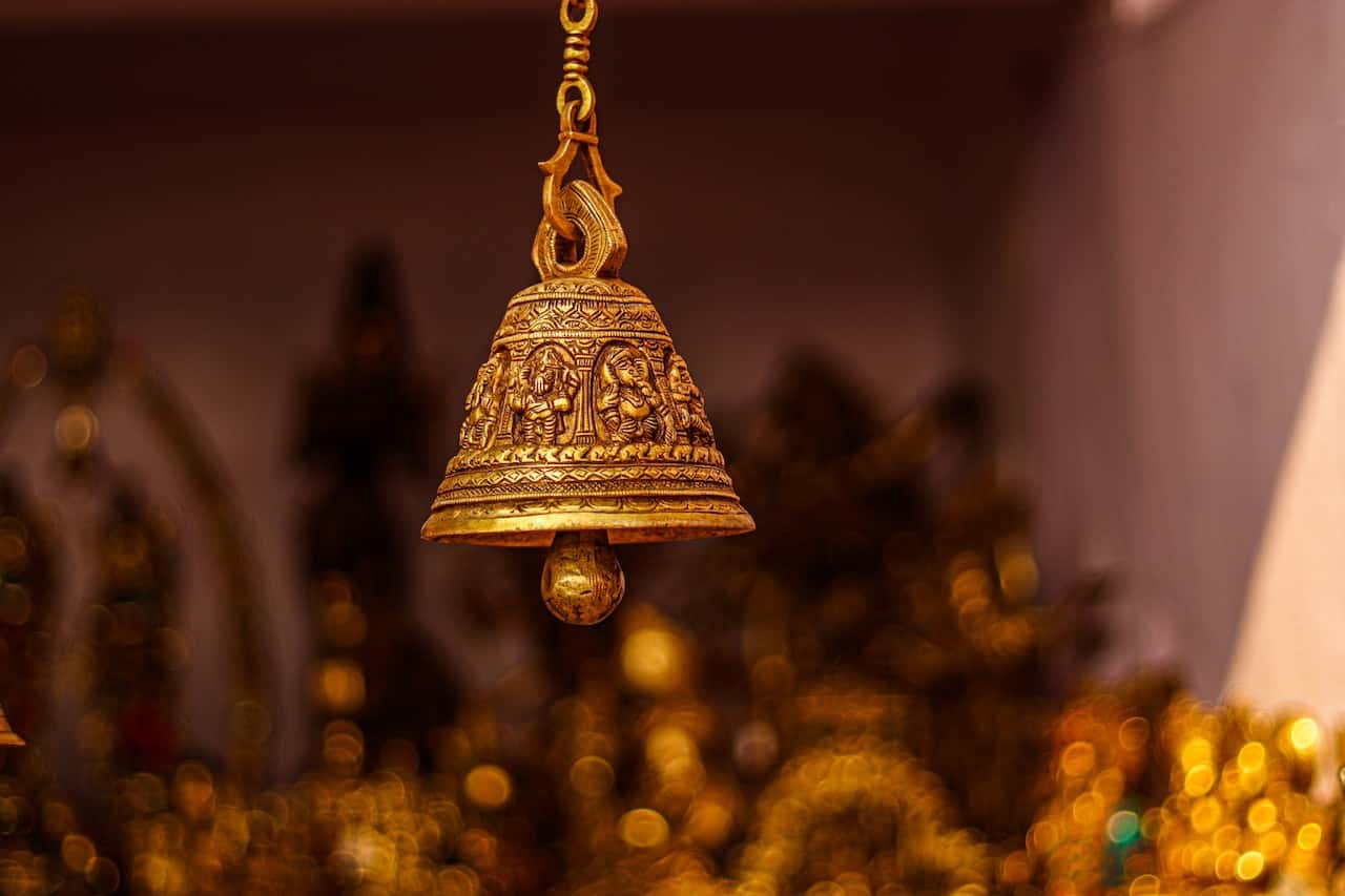 Sacred brass wind chimes vastu bell with Ganesha carvings in pooja room decor