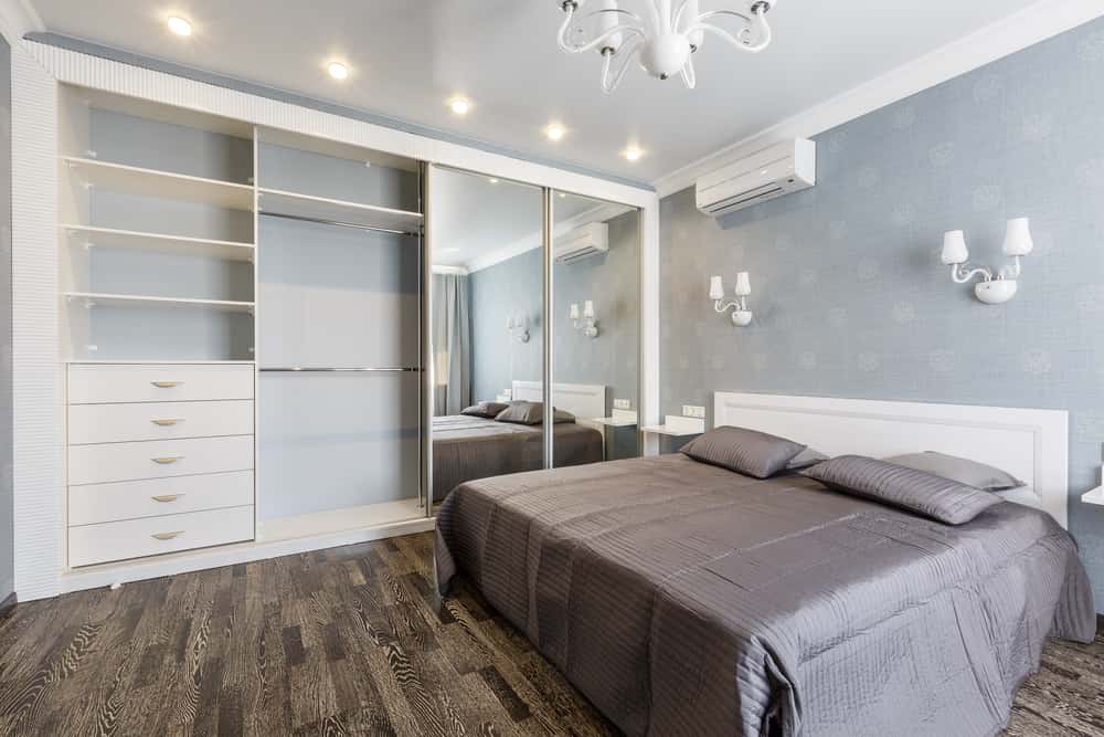 Modern l shaped wardrobe design with mirrored sliding doors in a stylish bedroom