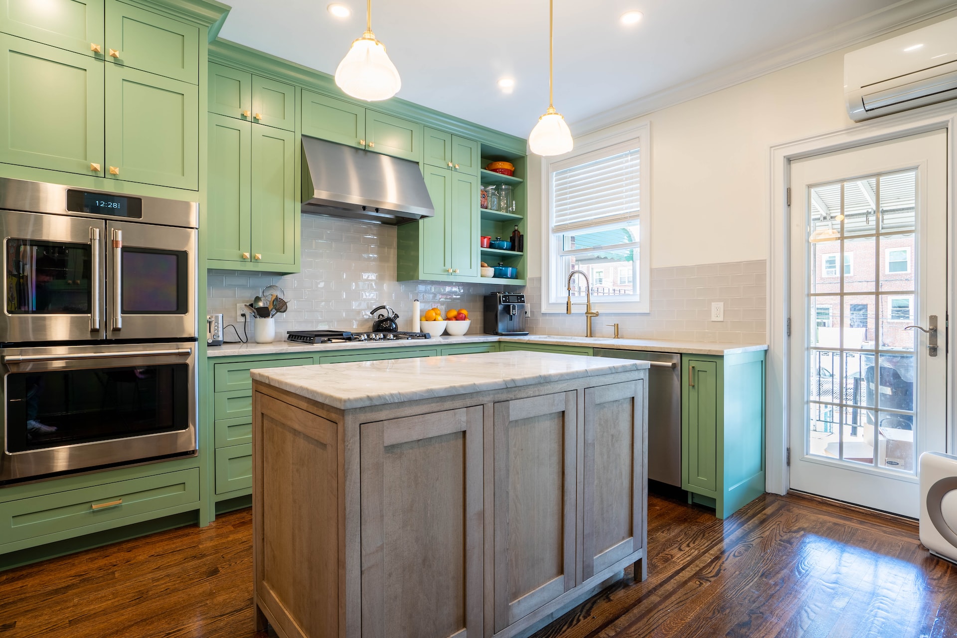 Elegant kitchen entrance design showcasing green cabinets and pendant lights