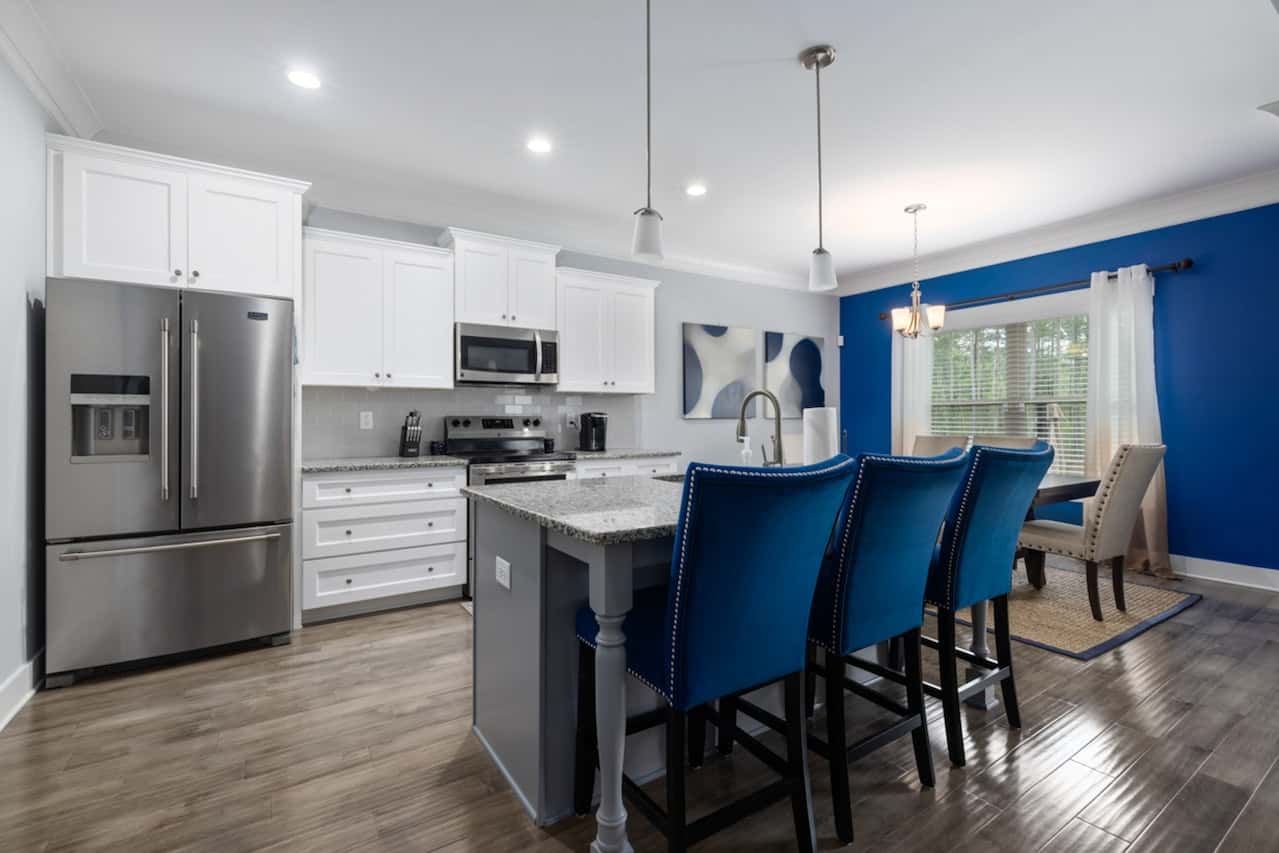 Modern kitchen entrance design with white cabinets and blue chairs