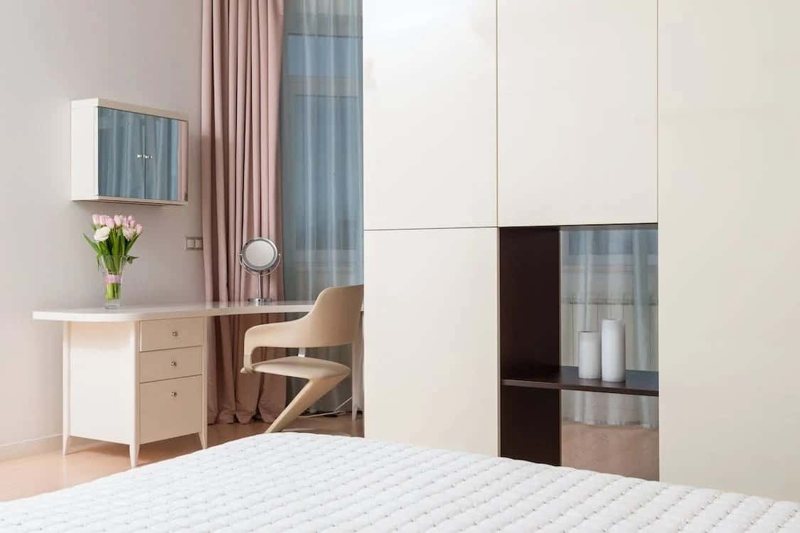 Elegant l shaped wardrobe design with built-in shelves beside a sleek study desk setup