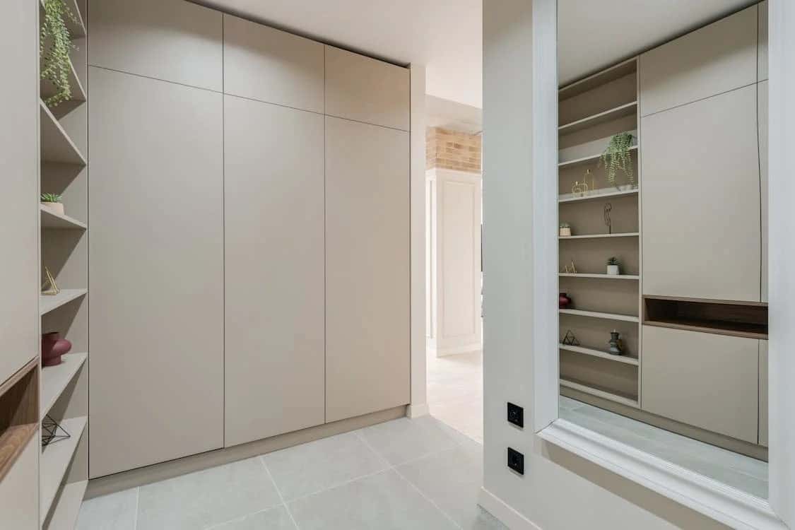 Sleek l shaped wardrobe design with built-in shelves in a modern neutral-toned bedroom