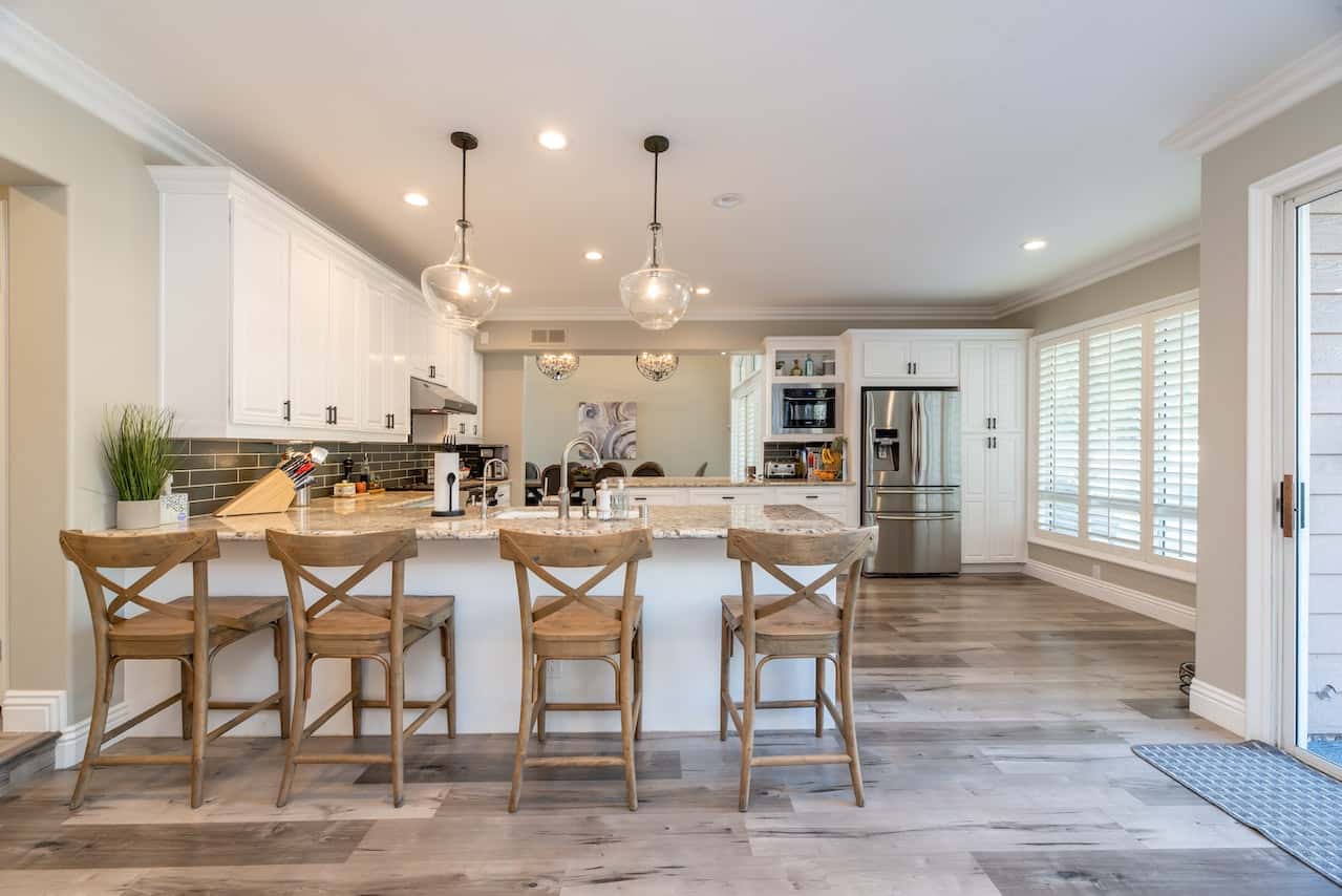 Contemporary kitchen entrance design with white cabinets and wooden stools