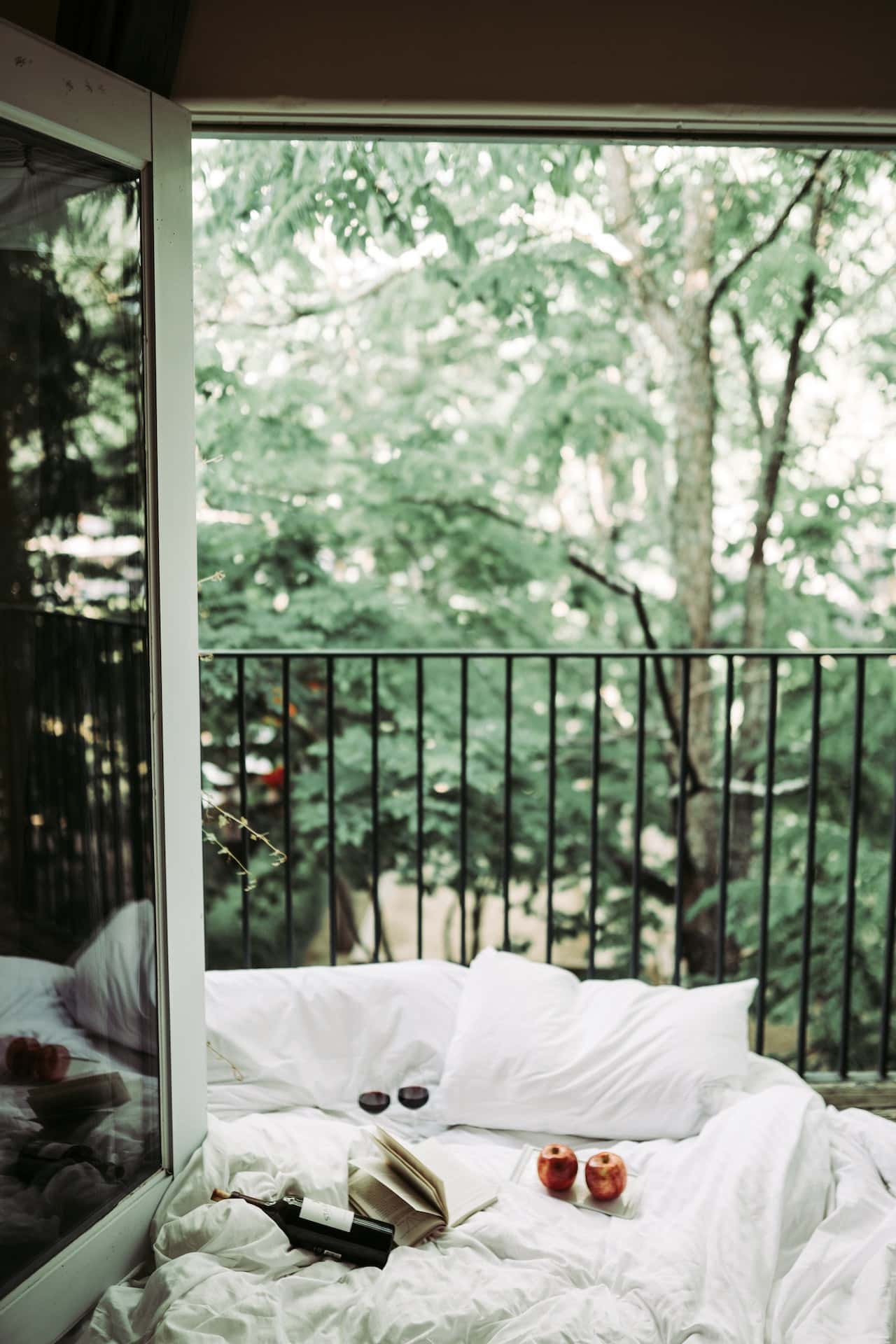 Cozy balcony sitout design with bed, pillows, and nature view for relaxation