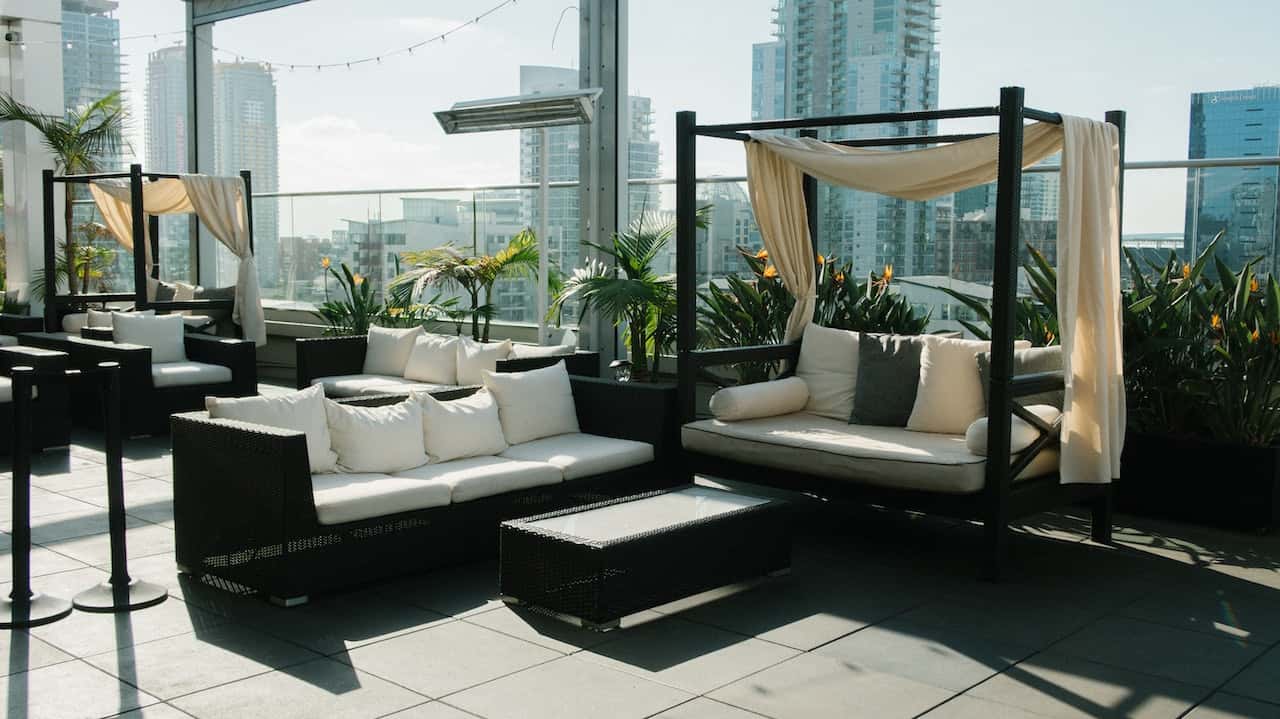 Modern rooftop sitout design with canopy seating, city views, and lush plants