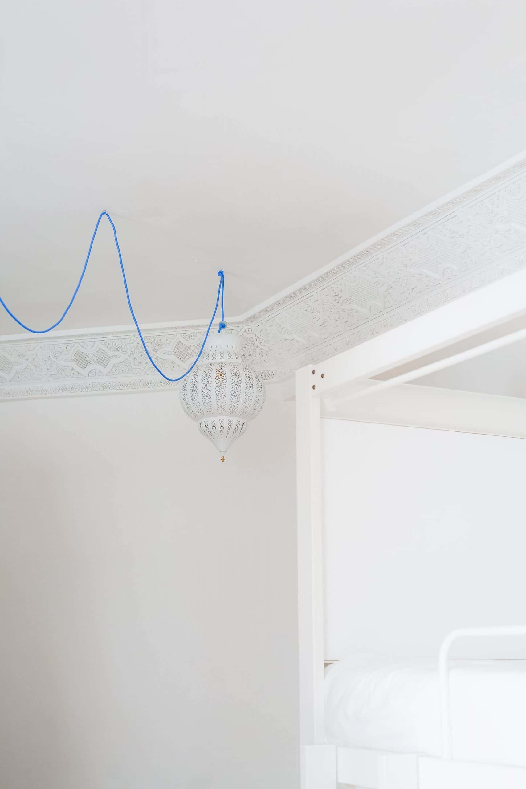 Elegant ceiling molding design with intricate carvings and Moroccan hanging lamp