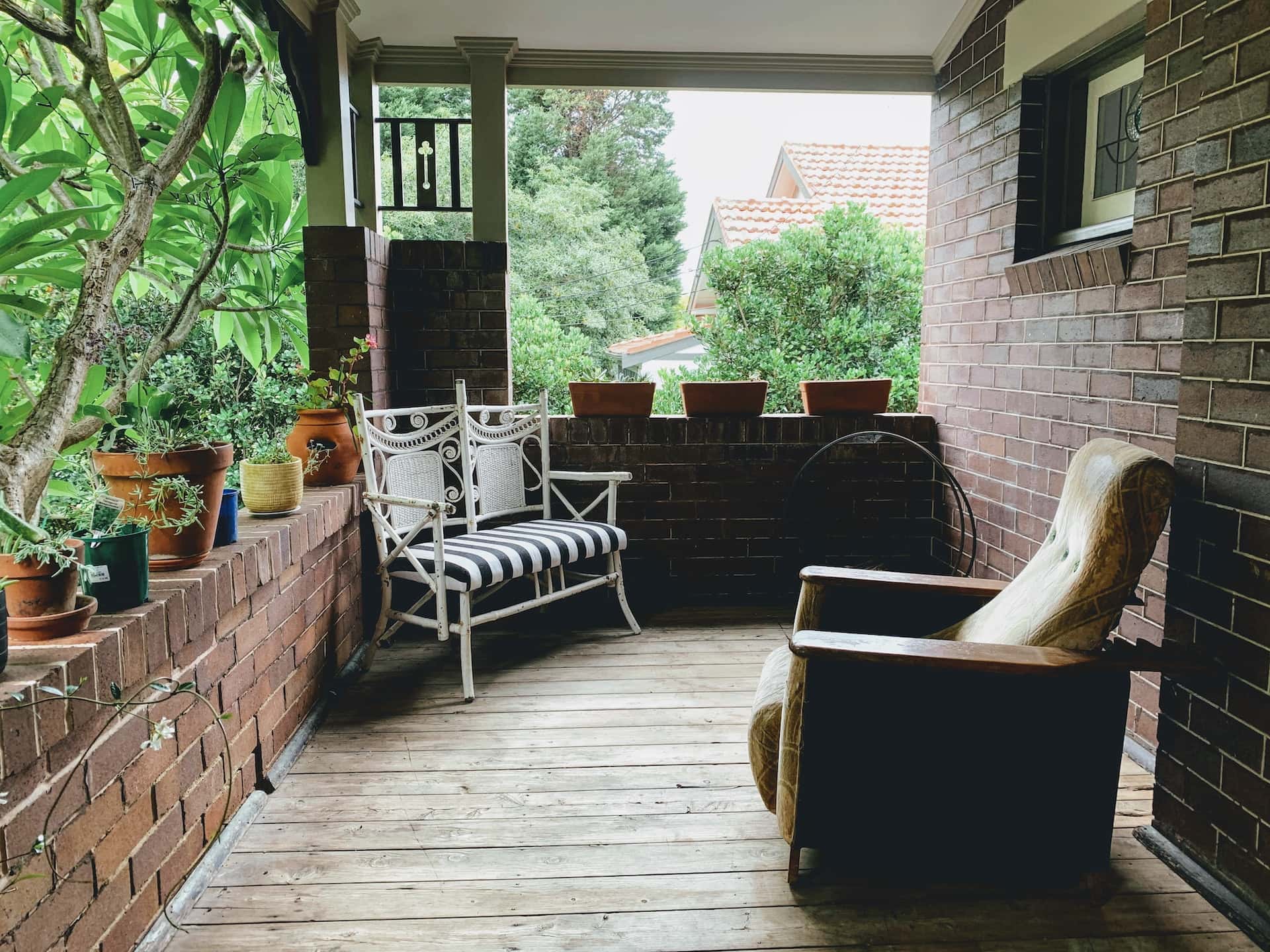 Cozy front sitout design with vintage chairs, potted plants, and brick walls