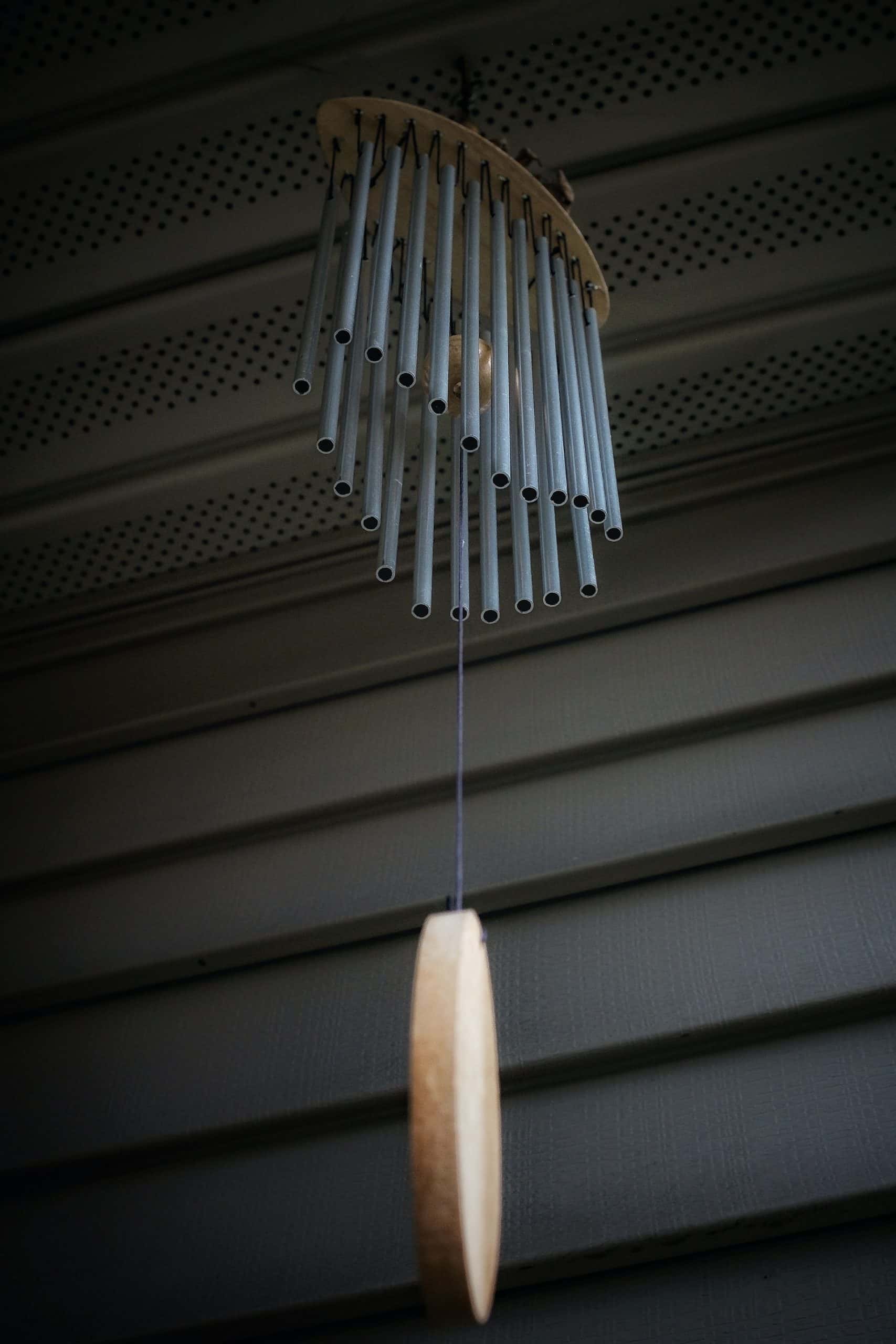 Modern wind chimes vastu element with metal rods hanging under a shaded roof