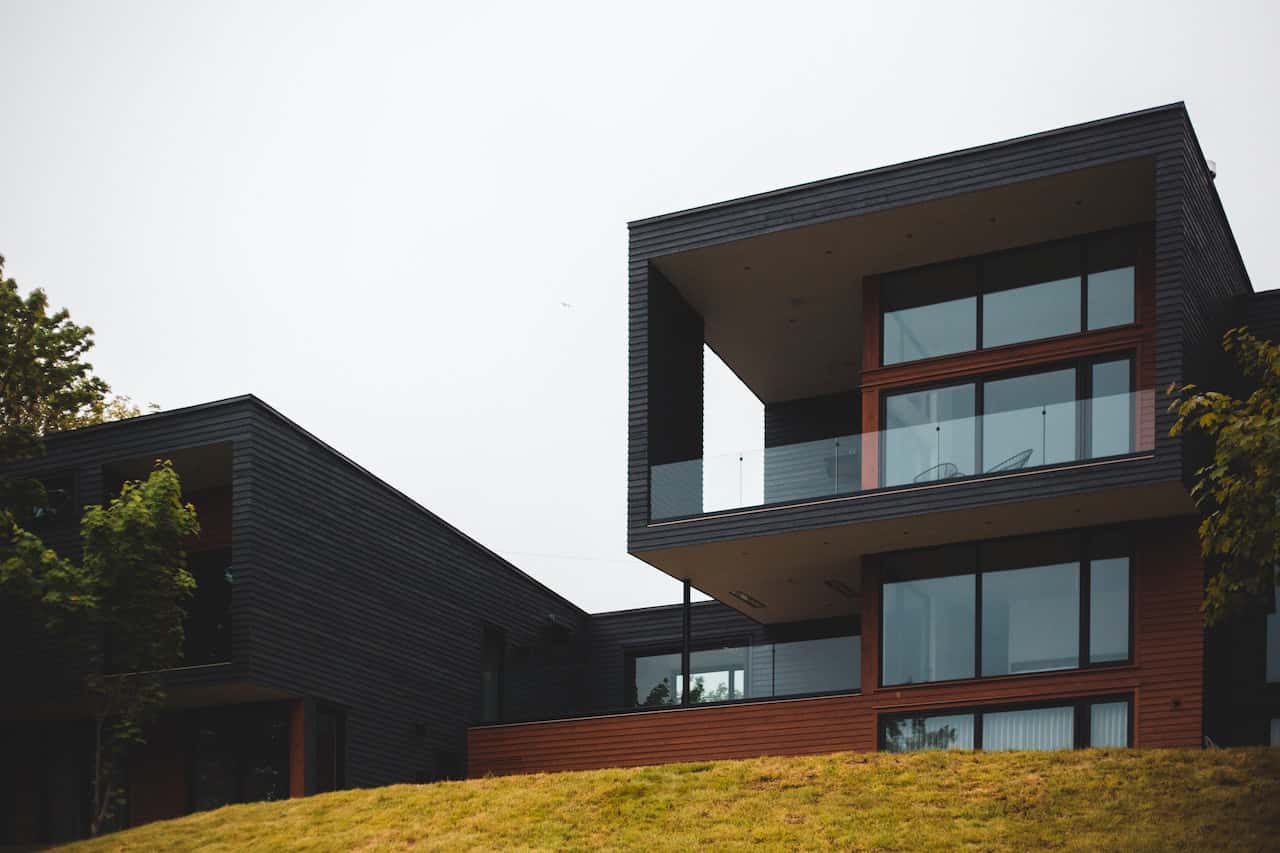 Modern elevation glass designs with dark cladding and glass balconies on sloped terrain