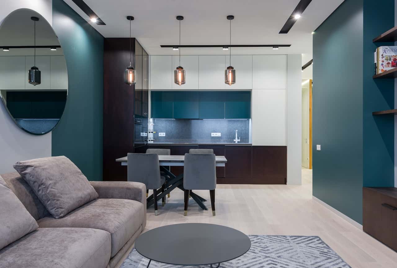 Compact sleek kitchen modular designs with teal cabinetry and pendant lights in living space