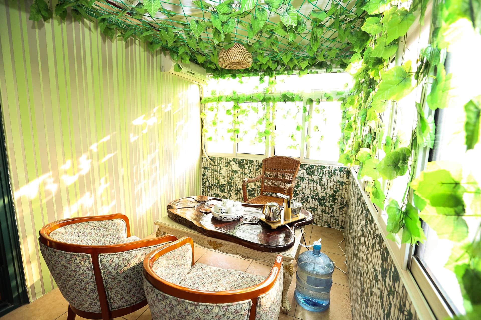 Nature-themed closed balcony ideas with greenery and vintage tea seating