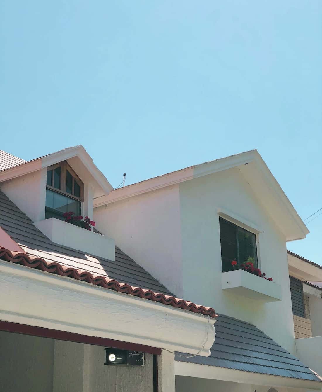 Modern mangalore tile roof home with pastel walls, planters, and dormer windows