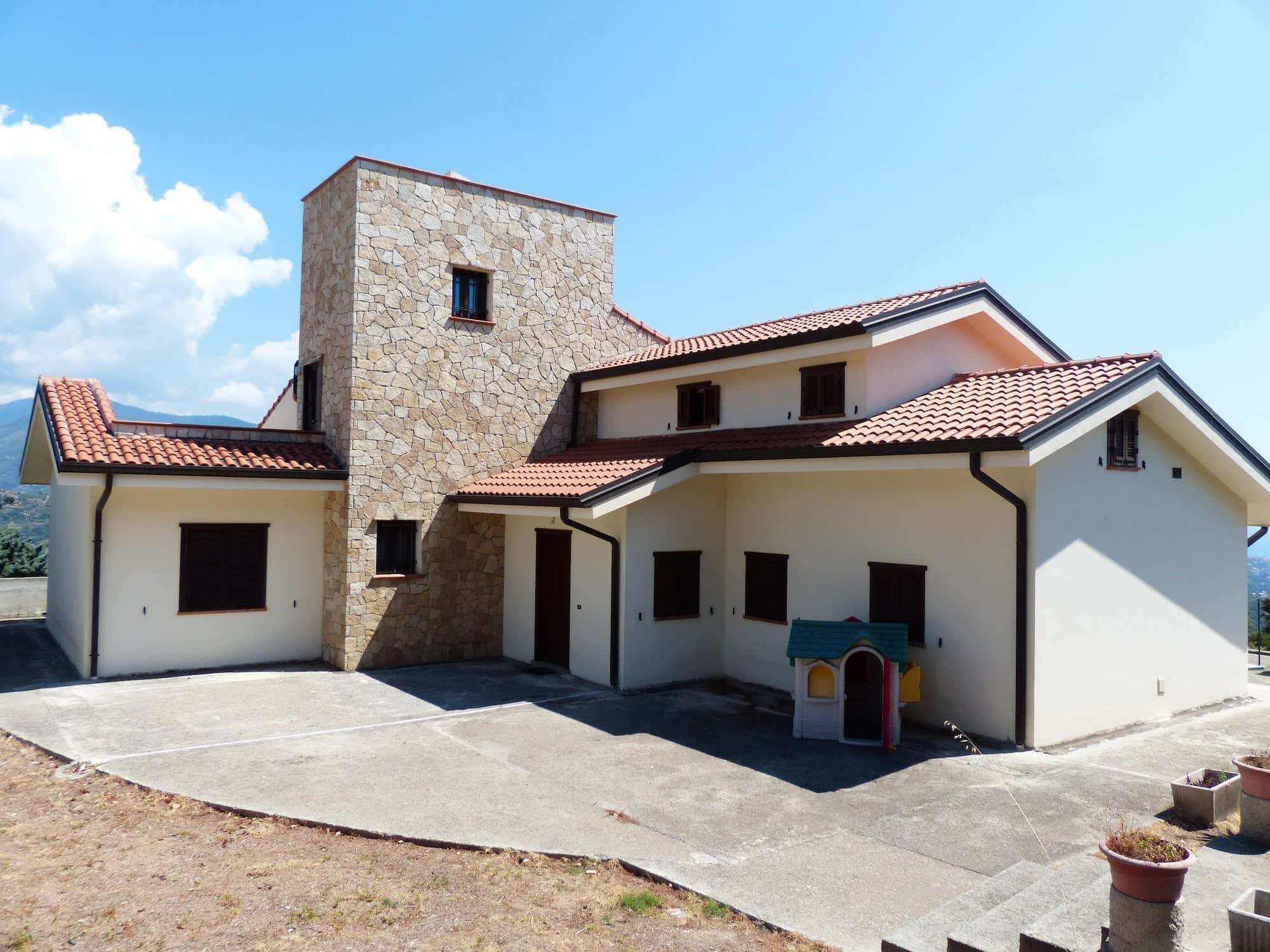 Modern mangalore tile roof villa with stone accent and multi-level roof design