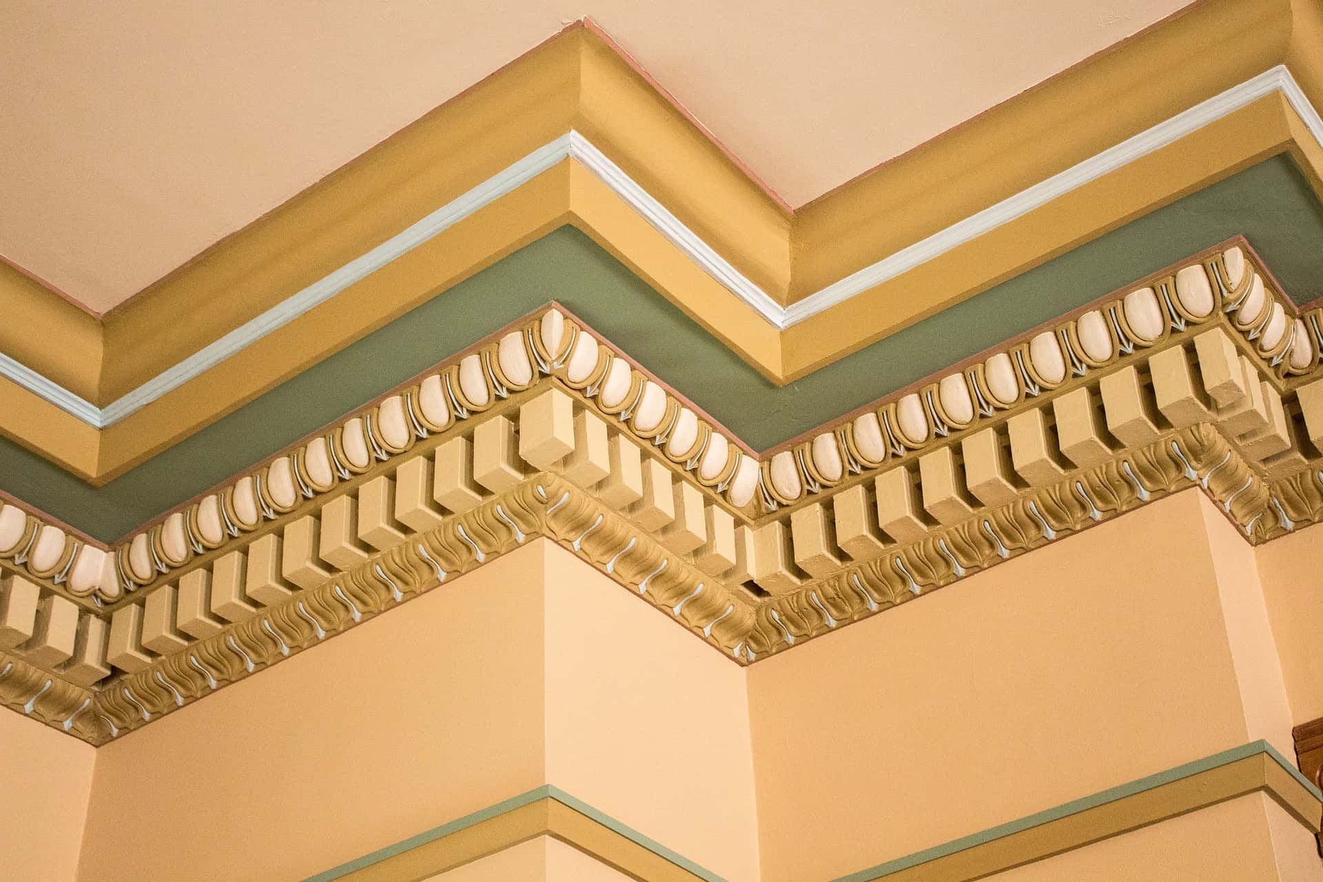 Ornate crown wall moulding designs with layered detailing in gold, cream, and green tones
