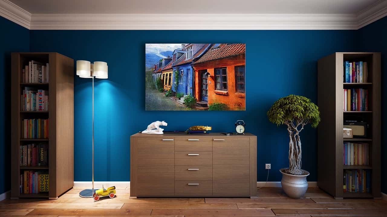 Modern room with blue walls, white crown wall moulding designs, and colorful artwork