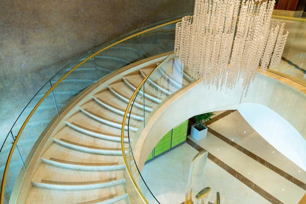 Curved staircase glass railing design with luxury chandelier