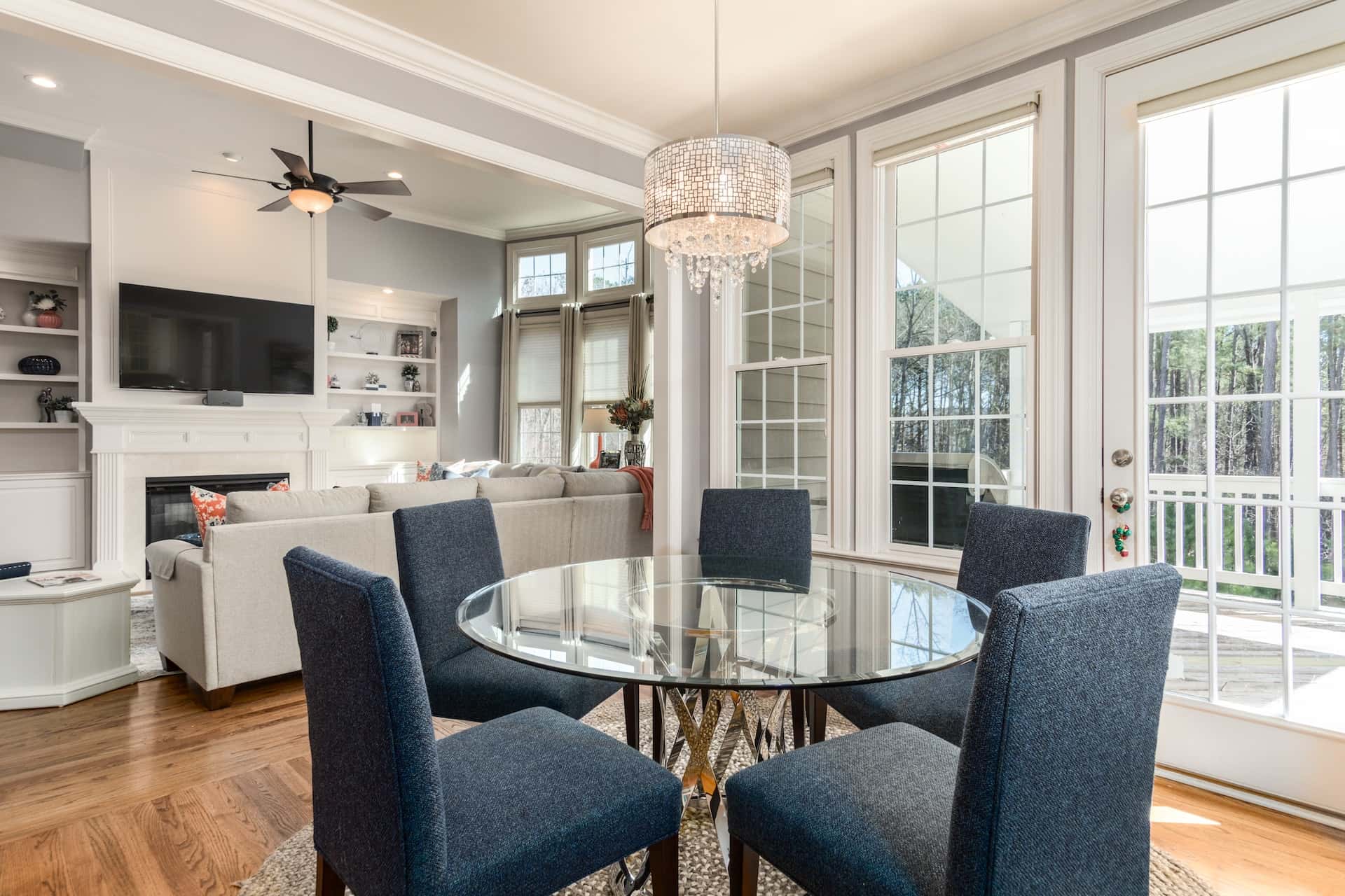 Bright dining area with glass table, blue chairs, and elegant wall moulding designs