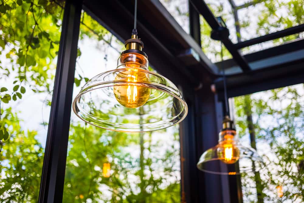 Latest glass ceiling design featuring modern hanging lights and leafy backdrop