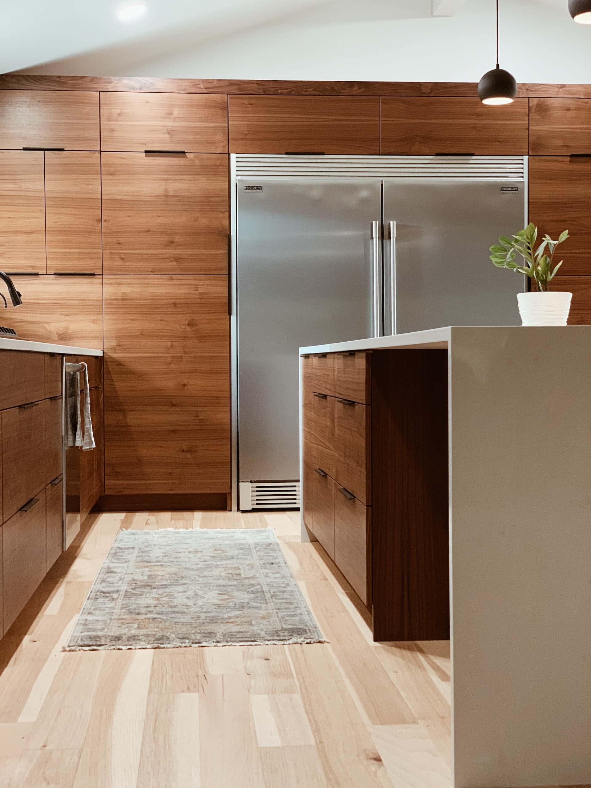 Natural sleek kitchen modular designs with wood cabinetry island counter and stainless fridge
