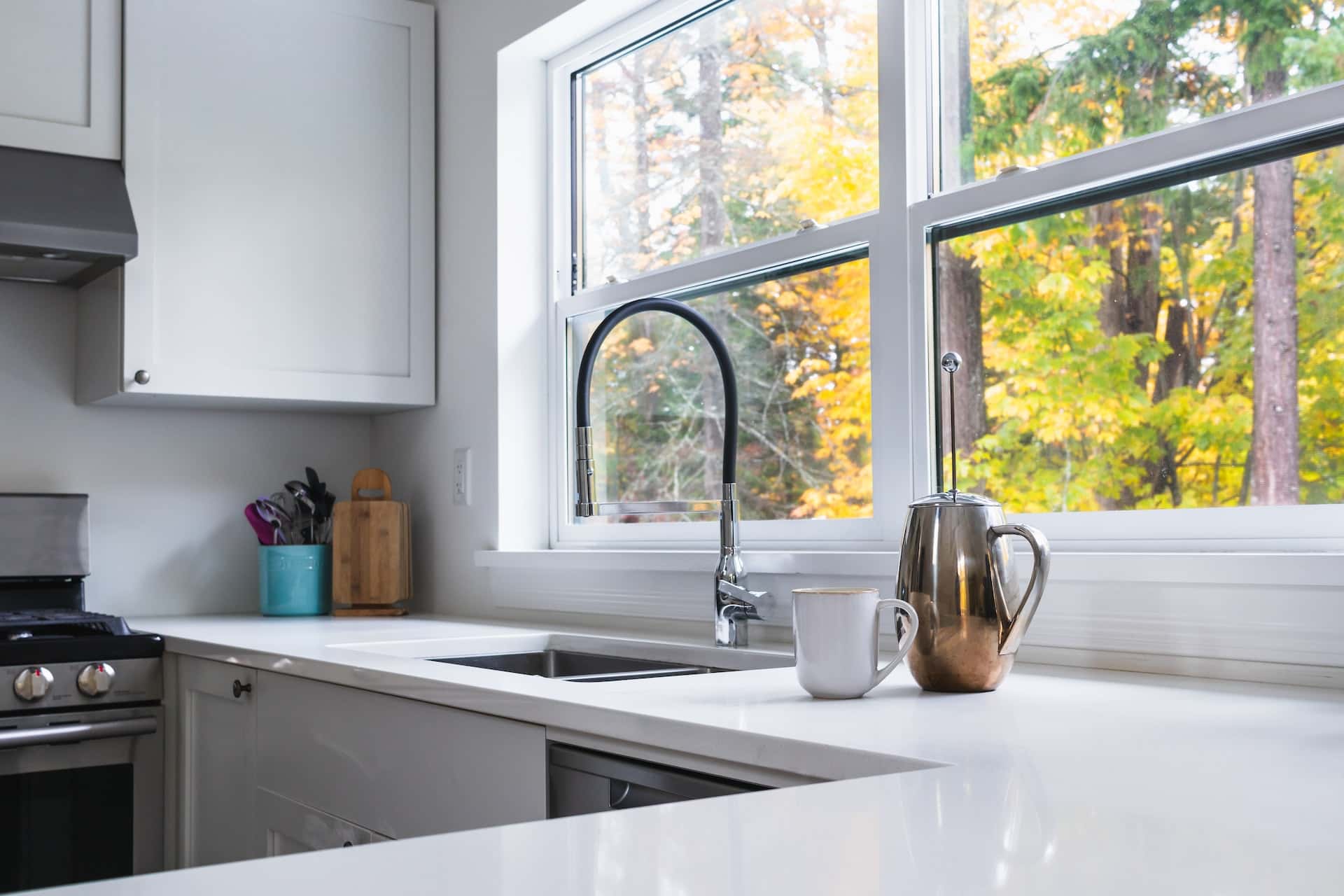 Modern kitchen sink design with white counter and large window view