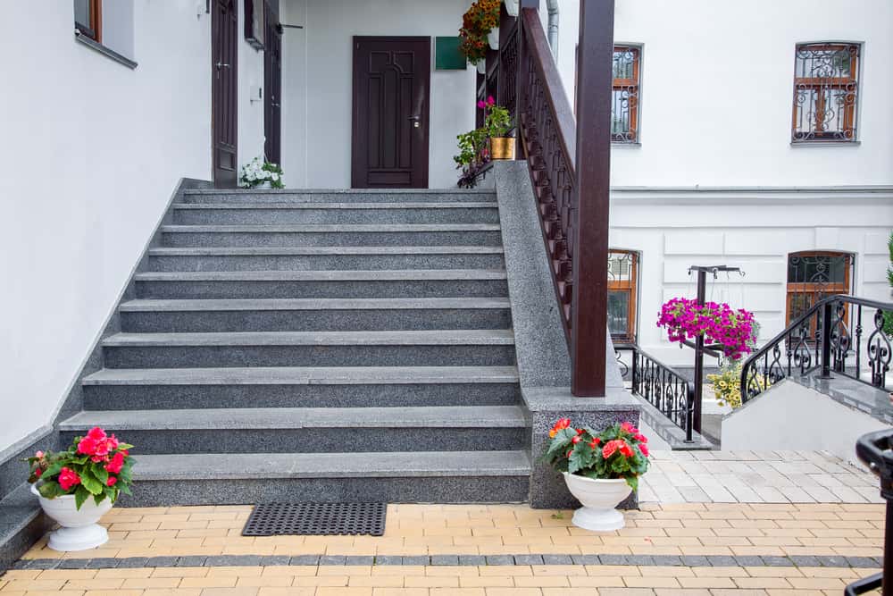 Outdoor staircase tile designs complement this cozy entry with floral decor