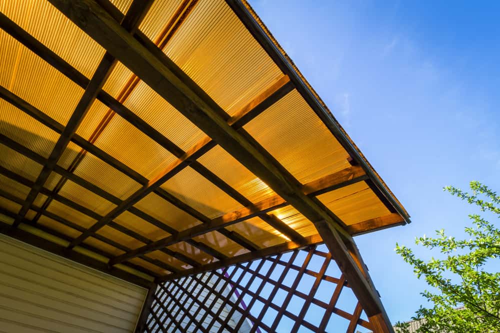 Sunlit polycarbonate roof design with wooden framing for stylish outdoor weather protection